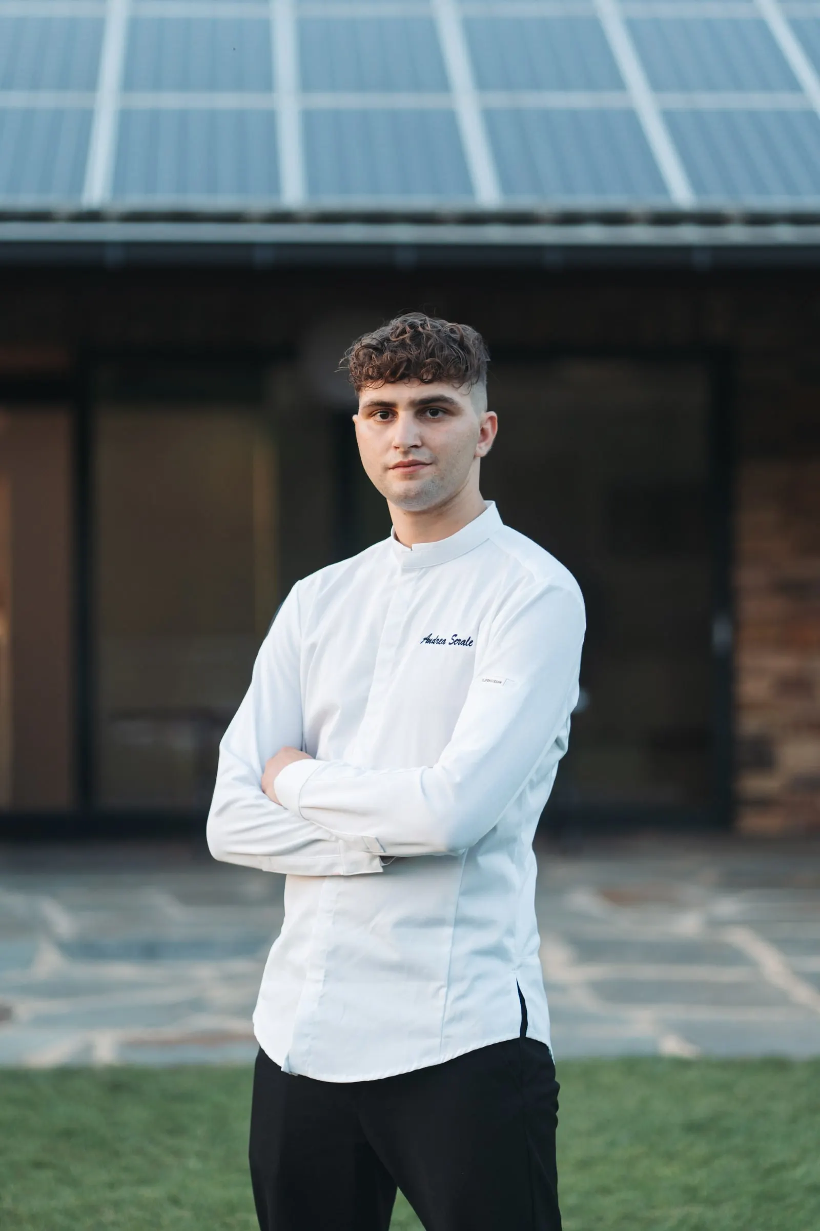Andrea Serale a braccia incrociate, in giacca da chef nel cortile di Villa San Lorenzo